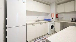 A compact kitchen with a washing machine, a sink, and a toaster.