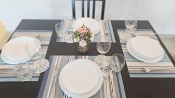 Una tavola imbandita con piatti, bicchieri e posate, decorata con un'elegante composizione floreale.