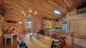 Interior de una cabaña de madera con comedor, cocina y un cartel que indica un servicio de alquiler.