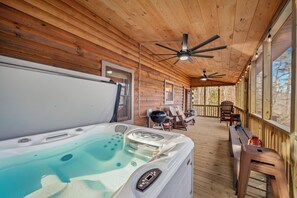 Eine Holzhütte mit Whirlpool, Deckenventilatoren und einer Terrassenlounge.