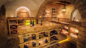 A wine cellar with stone walls, wooden shelves, and wine racks. - Hotel Barbarahof (Saalbach-Hinterglemm)