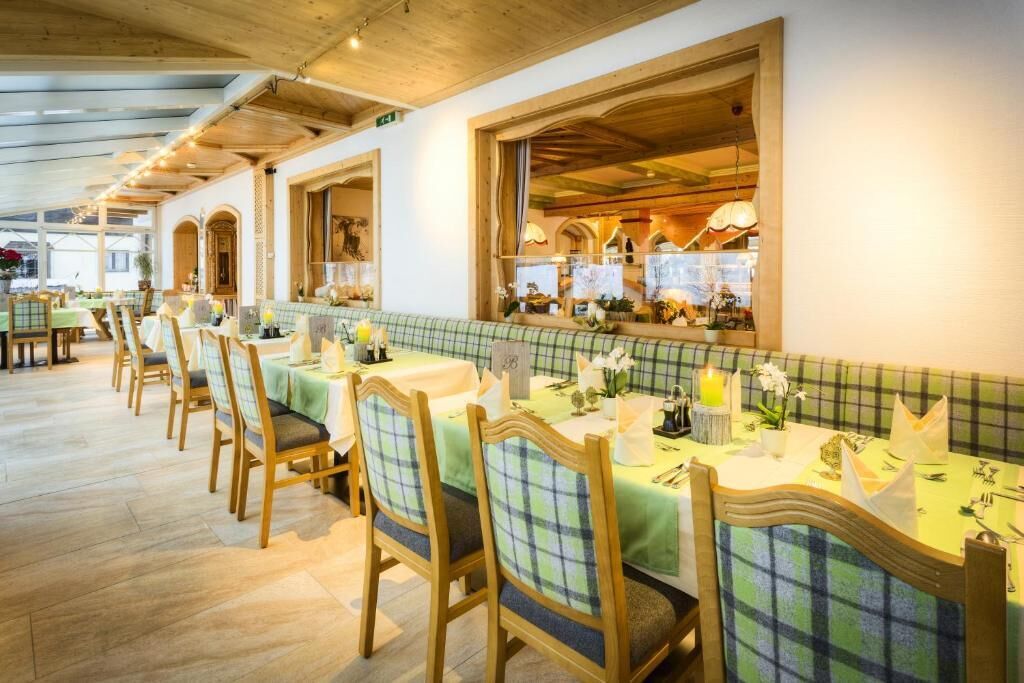 A restaurant with wooden tables and chairs, a tiled backsplash, and a view of the interior.