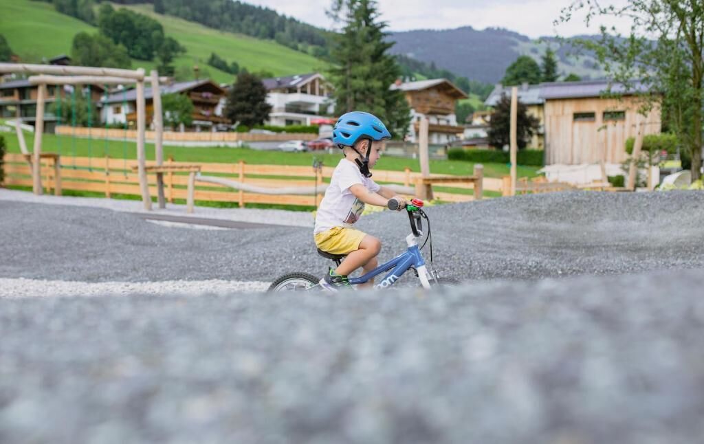 Un enfant à vélo sur une piste cyclable, avec un paysage rural en arrière-plan.