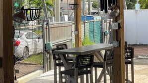 Une terrasse extérieure en bois, avec une table et des chaises, un luminaire suspendu et un ventilateur de plafond.