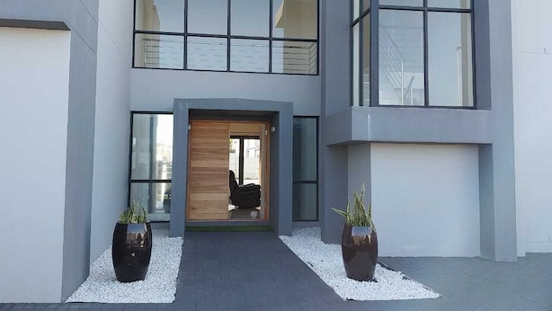 Un bâtiment moderne doté d’une double entrée, de grandes fenêtres et de deux plantes en pot.