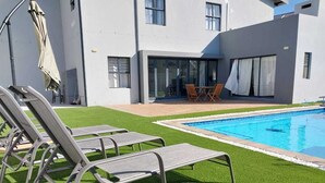 Un bâtiment moderne doté d’une piscine, d’un espace extérieur aménagé et d’une pelouse artificielle.