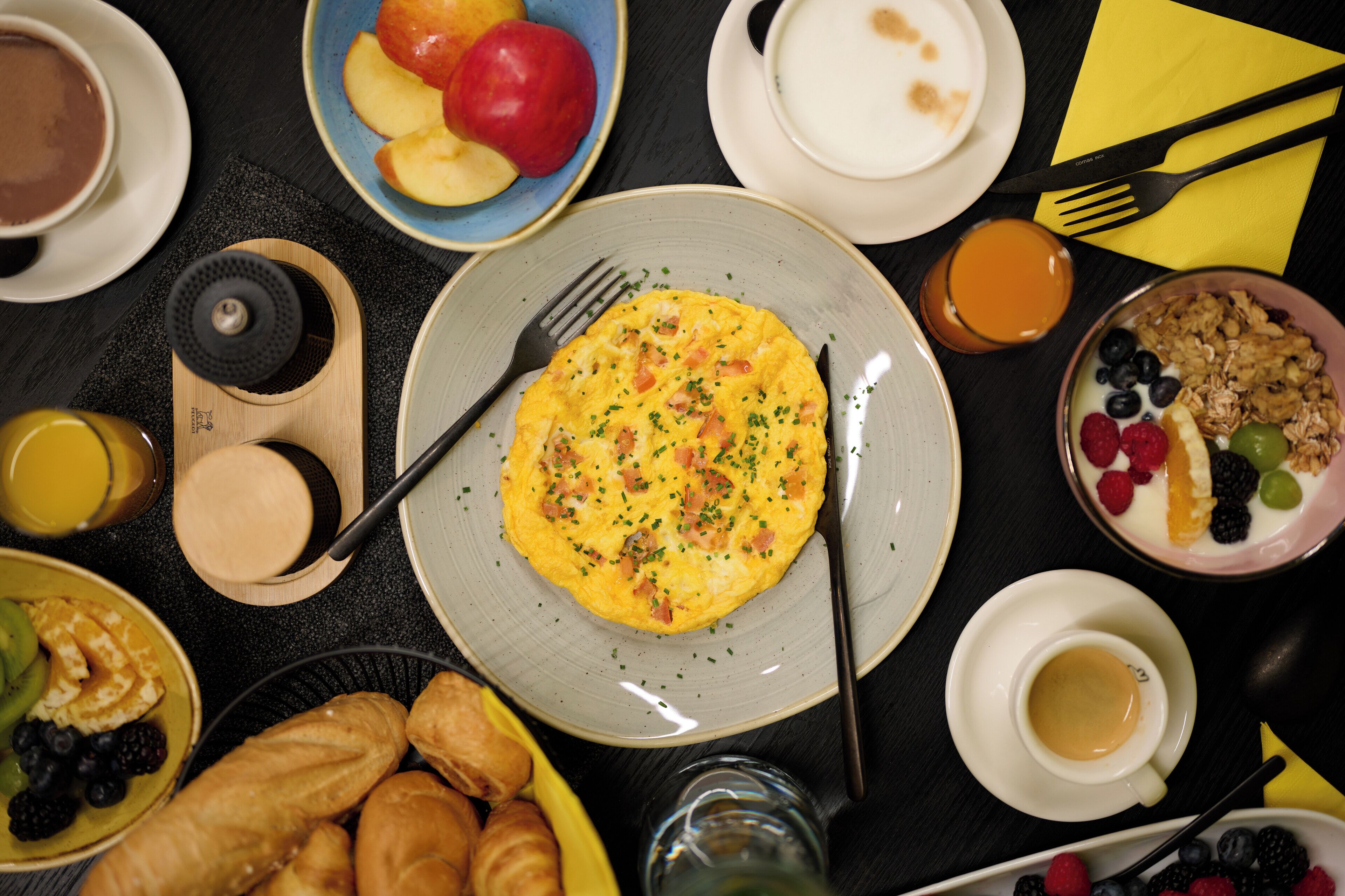 A breakfast setting with various food items and drinks on a table.