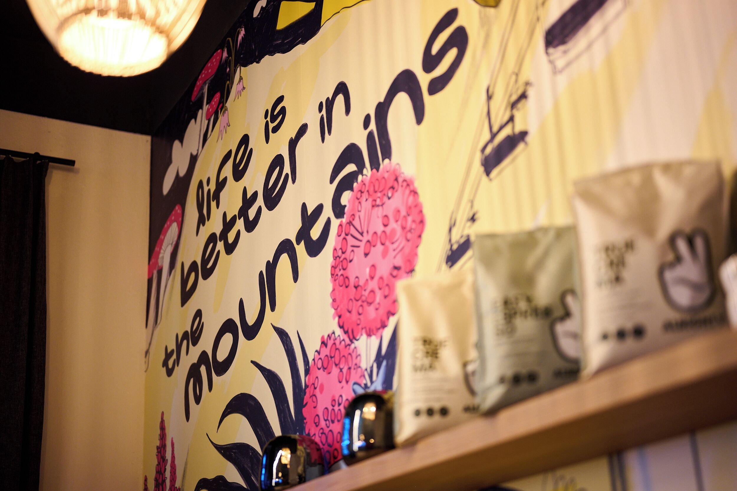 Pared con una cita motivacional, estante con bolsas y una lámpara decorativa.