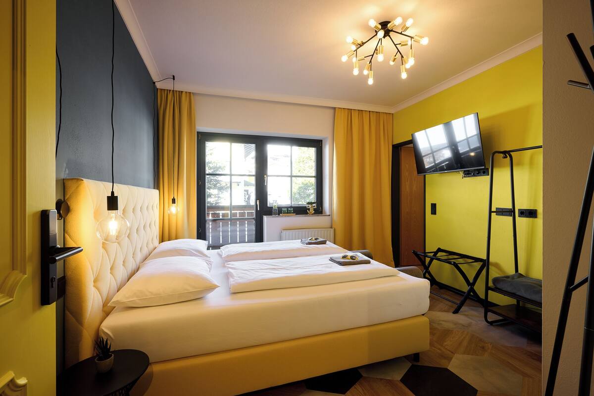 Une chambre d’hôtel avec un lit, une télévision, une fenêtre et un balcon.