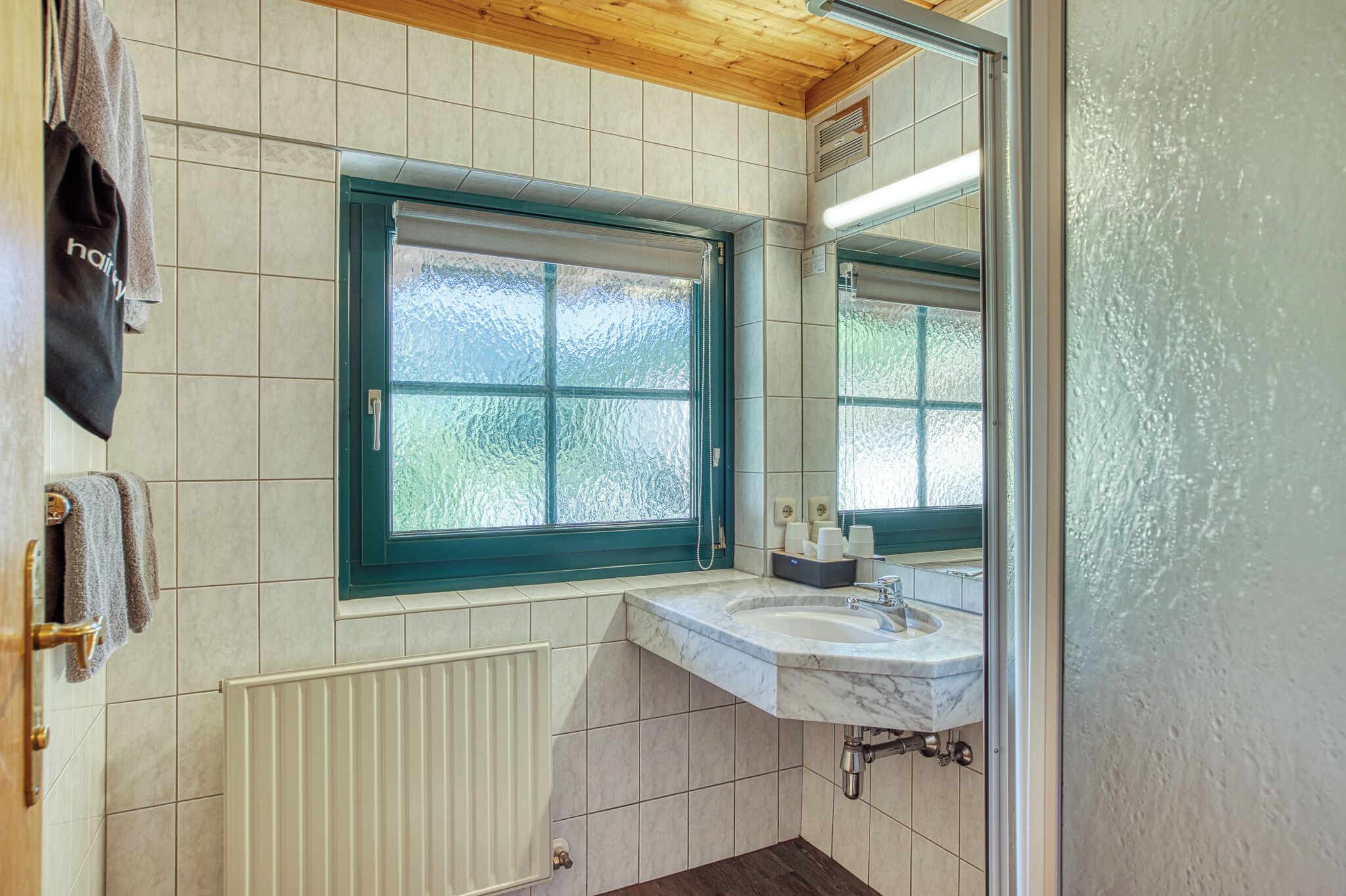 A bathroom with a window, a sink, and a towel rack.