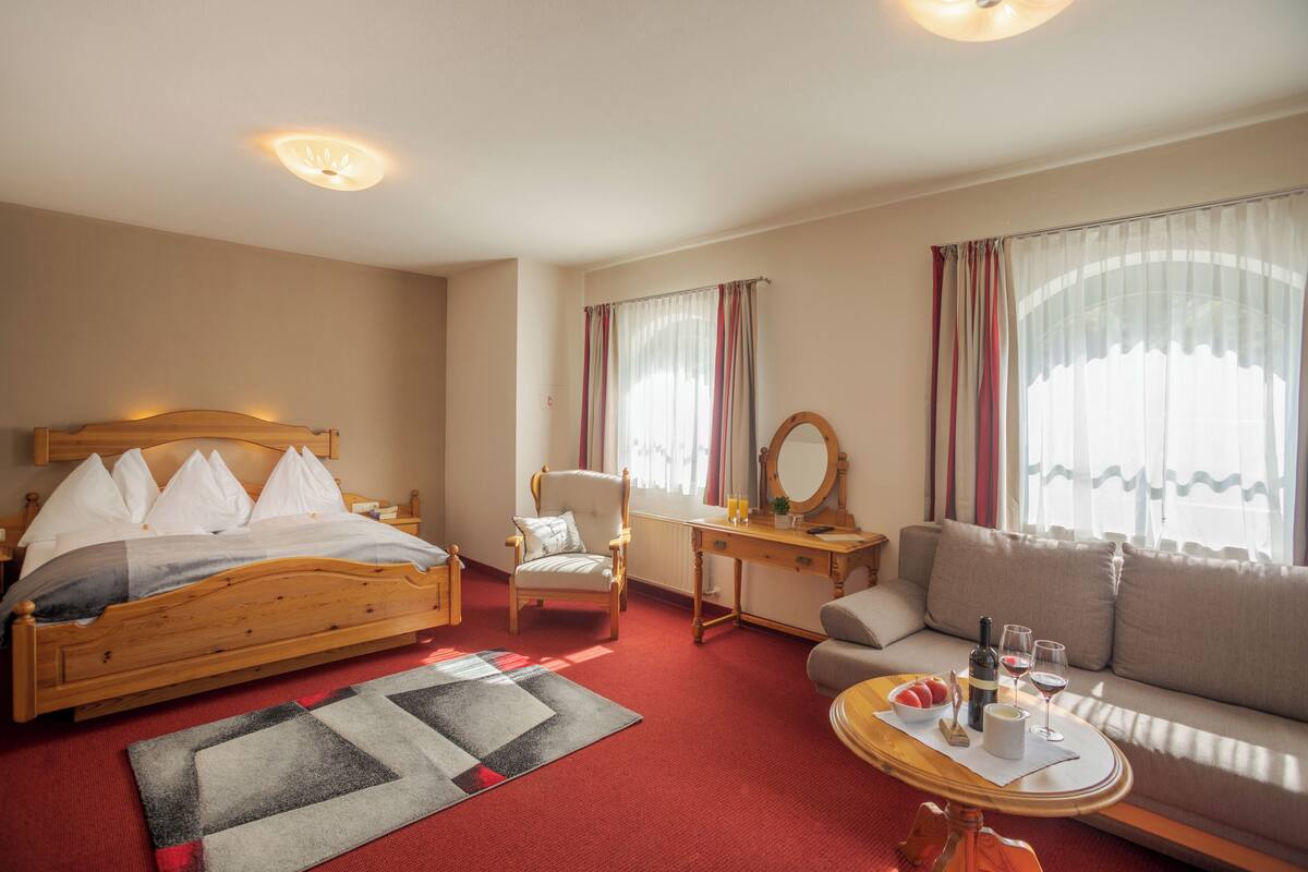 Une chambre d’hôtel avec un lit en bois, un canapé, un bureau et une chaise.