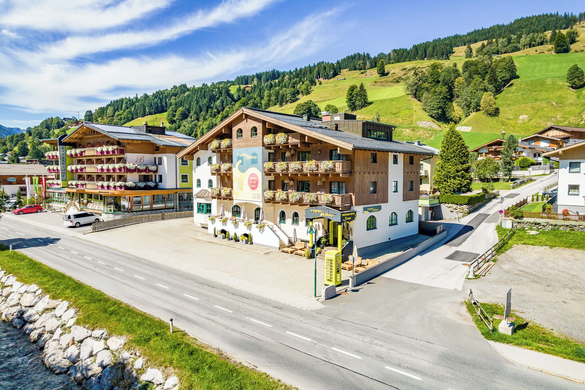 Un hotel con balcón, un cartel y vistas al follaje circundante.