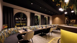 Un restaurante con una barra larga, mesas tipo cabina y una zona de bar.