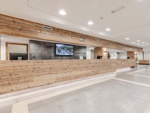 A reception area with a wooden reception desk, a flat-screen TV mounted on the wall, and a sign indicating the location as 'RESIDENCE'. - Hotiday Apartments La Thuile (La Thuile)