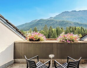A balcony with two flower planters, a table, and chairs. - Hotiday Apartments La Thuile (La Thuile)
