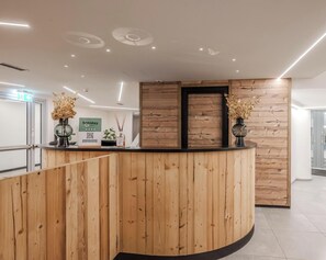 A reception desk with wooden paneling, two vases with dried flowers, and a sign that reads "happy day". - Hotiday Apartments La Thuile (La Thuile)