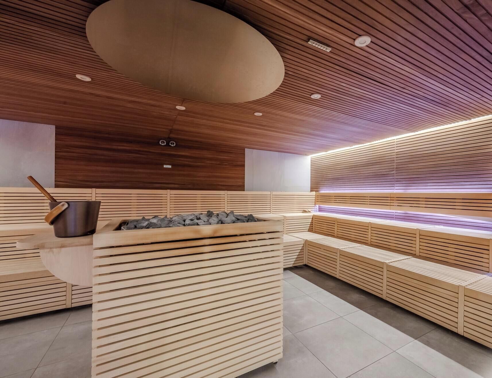 Una sauna con bancos de madera y un elemento central de piedra.