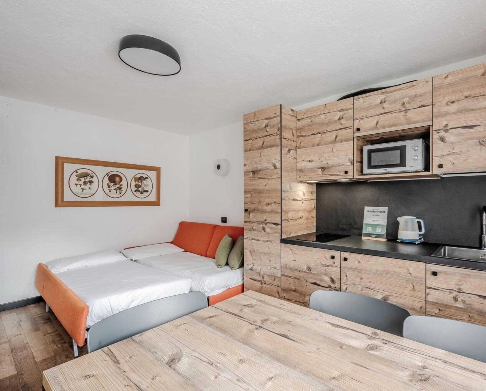 A compact room with a bed, a table, and a kitchenette.