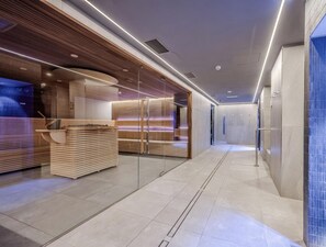 A modern hotel lobby with a reception desk, seating area, and a glass partition. - Hotiday Apartments La Thuile (La Thuile)