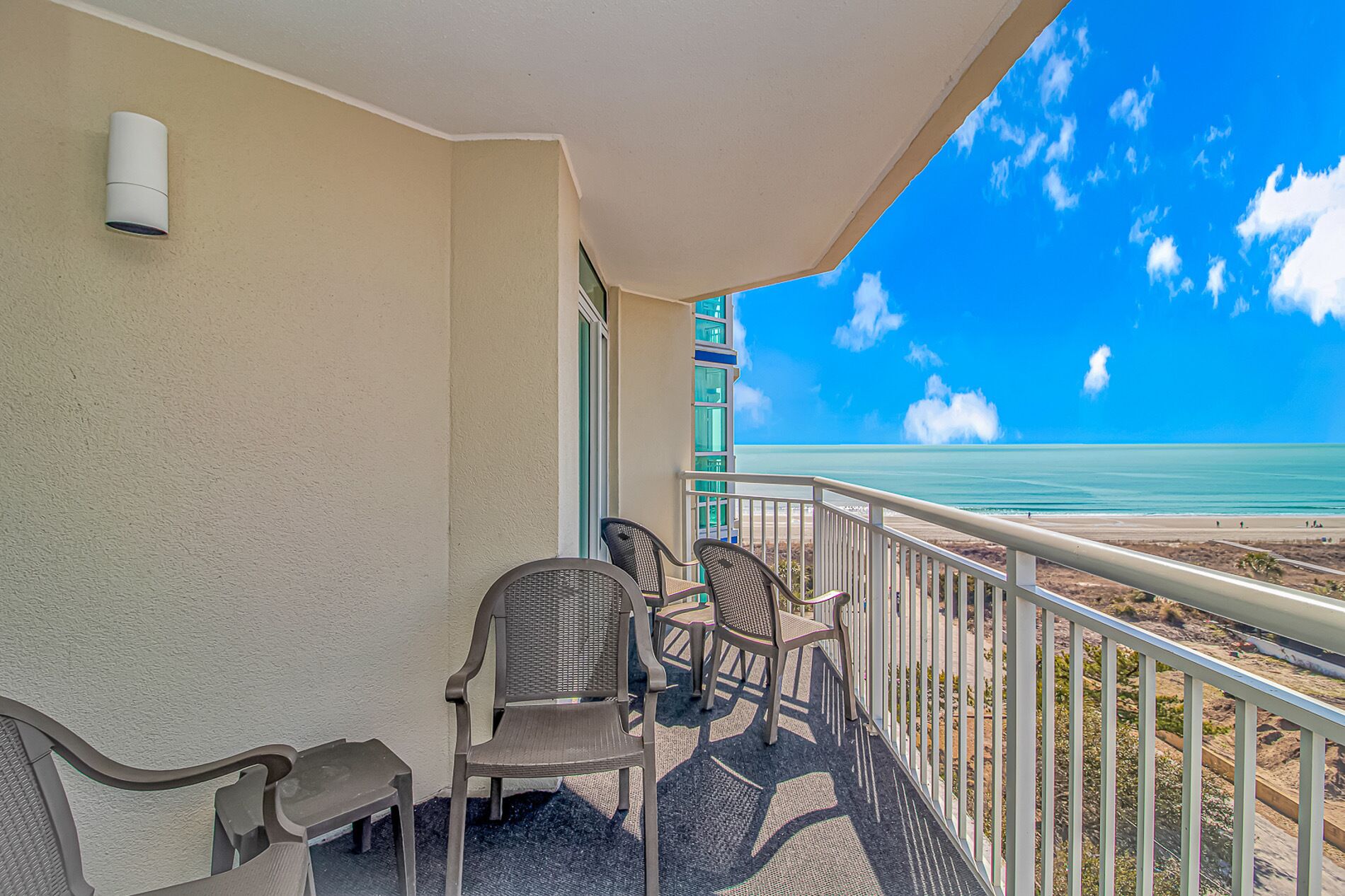A balcony with chairs and a view of the ocean.