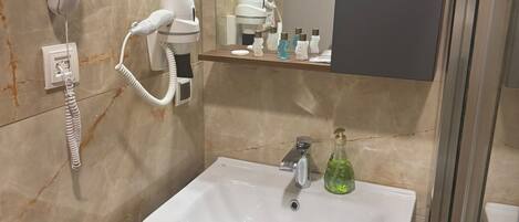 Un baño con un lavamanos blanco, un secador de pelo, un espejo y un teléfono.