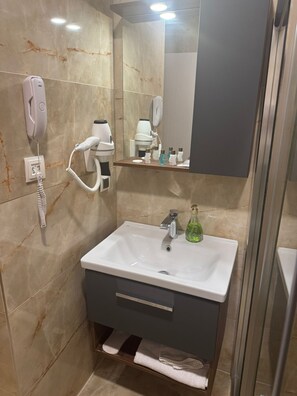 A bathroom with a white sink, a hairdryer, a mirror, and a phone. - Pacis Antakya (Antakya)