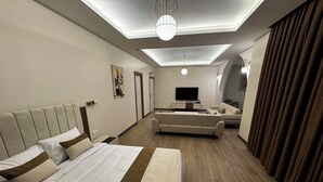 Ett modernt hotellrum med en stor säng, en soffa, en TV och en taklampa.