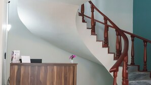 A reception desk with a wooden finish, a marble staircase with wooden railings, and a wall with a teal accent. - Estancia monraz (Guadalajara)