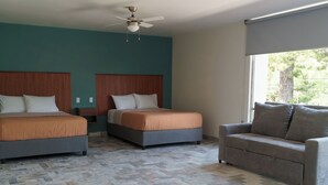 A hotel room with two beds, a sofa, a ceiling fan, and a large window. - Estancia monraz (Guadalajara)