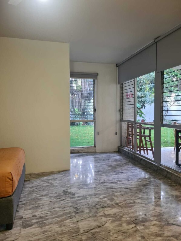 Una stanza con un letto, un'ampia porta-finestra scorrevole che dà su un balcone e un pavimento in marmo.