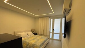 Ein modernes Schlafzimmer mit Bett, Nachttisch und einem an der Wand befestigten Fernseher.