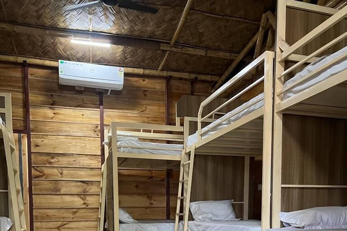 Dormitorio con literas, paredes de madera y ventilador de techo.