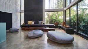 Ein modernes Interieur mit einem großen Fenster, einer dunklen Wand und einer Sitzecke mit Kissen und einer Vase.