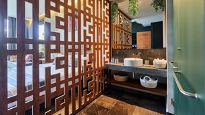 Ein modernes Badezimmer mit einer Holzwand, einem Waschbecken mit Spiegel und einer grünen Tür.