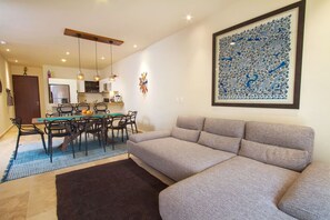Un salon avec un canapé, une table à manger, des chaises et, au fond, une cuisine.