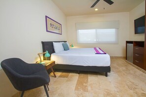 Une chambre à coucher avec un lit, un bureau, une chaise, une télévision et une fenêtre.