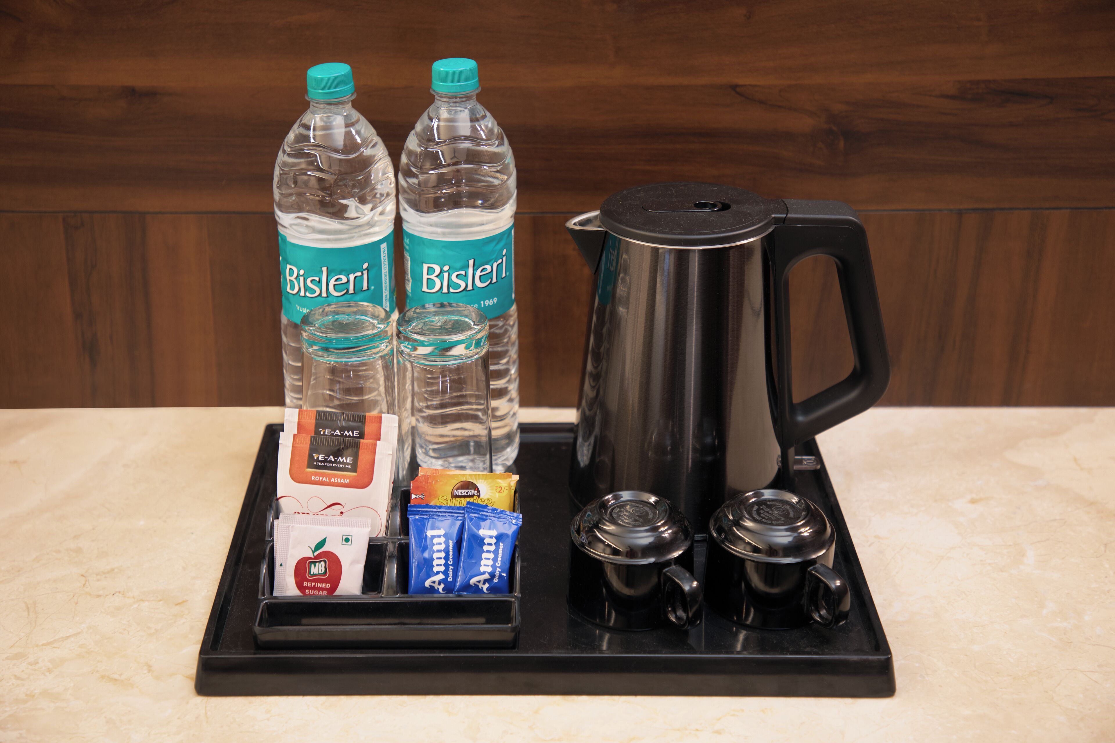 A coffee station with Bisleri water bottles, a coffee pot, and various coffee pods.
