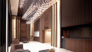 Eine moderne Lobby mit einem Marmortisch, Ledersofas und einer dekorativen Deckenleuchte.