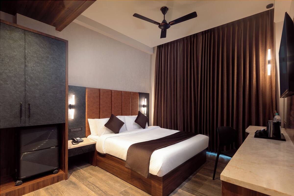 A modern hotel room with a large bed, a desk, a wardrobe, and a ceiling fan.