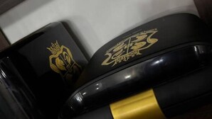 Deux récipients noirs ornés de motifs dorés et noirs, posés sur une surface en bois.