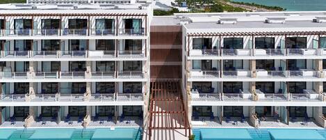 A hotel with multiple balconies, a swimming pool, and a view of the ocean.
