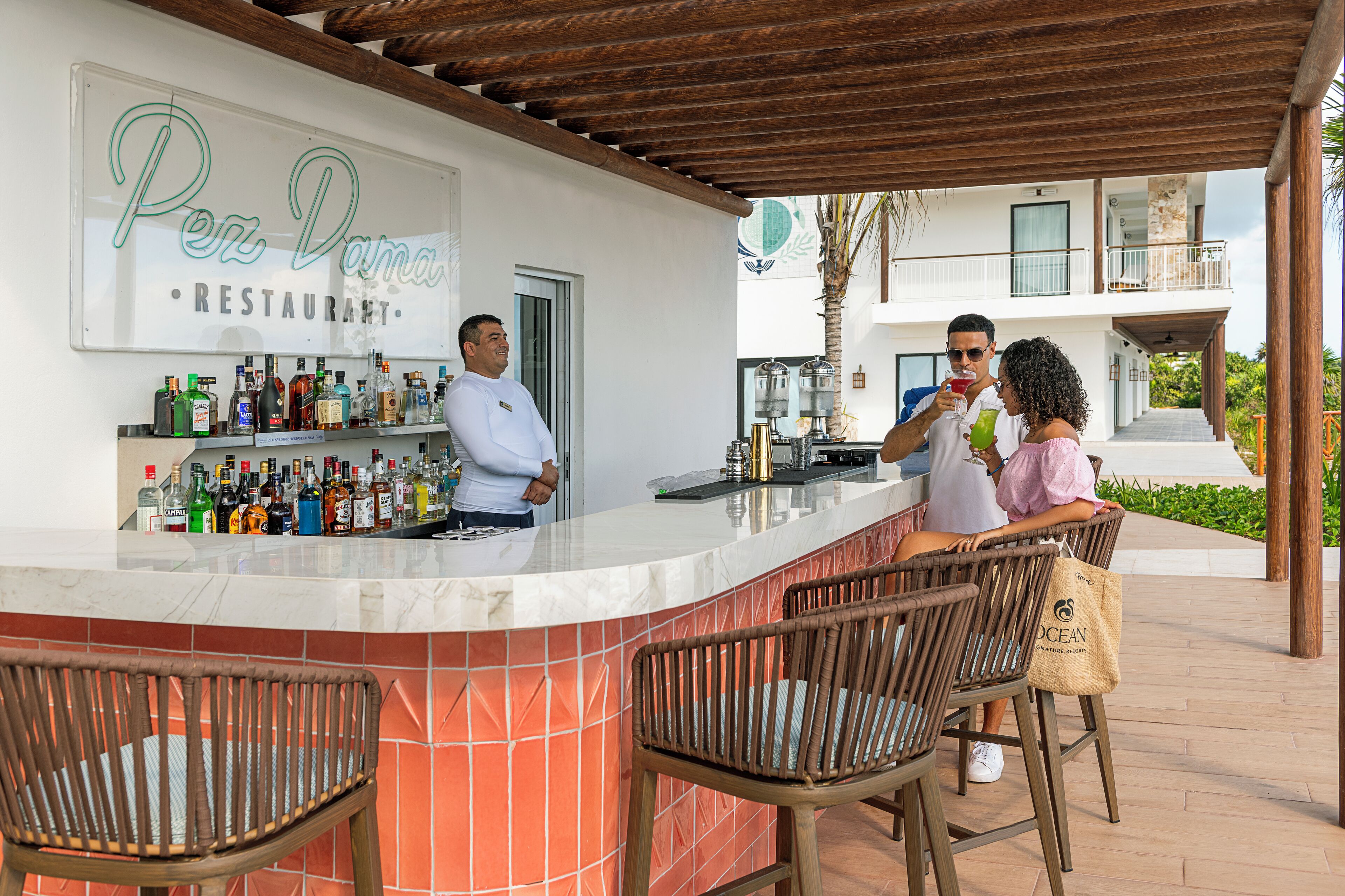 A bar area with a sign reading "Per Dama Restaurant," a bartender, and two patrons.
