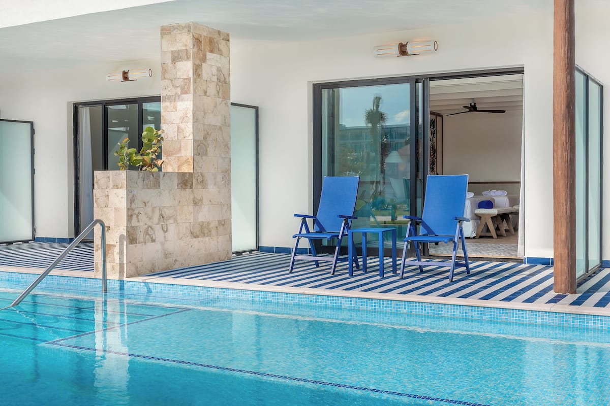 Una piscina con sillas azules y un pilar de piedra.