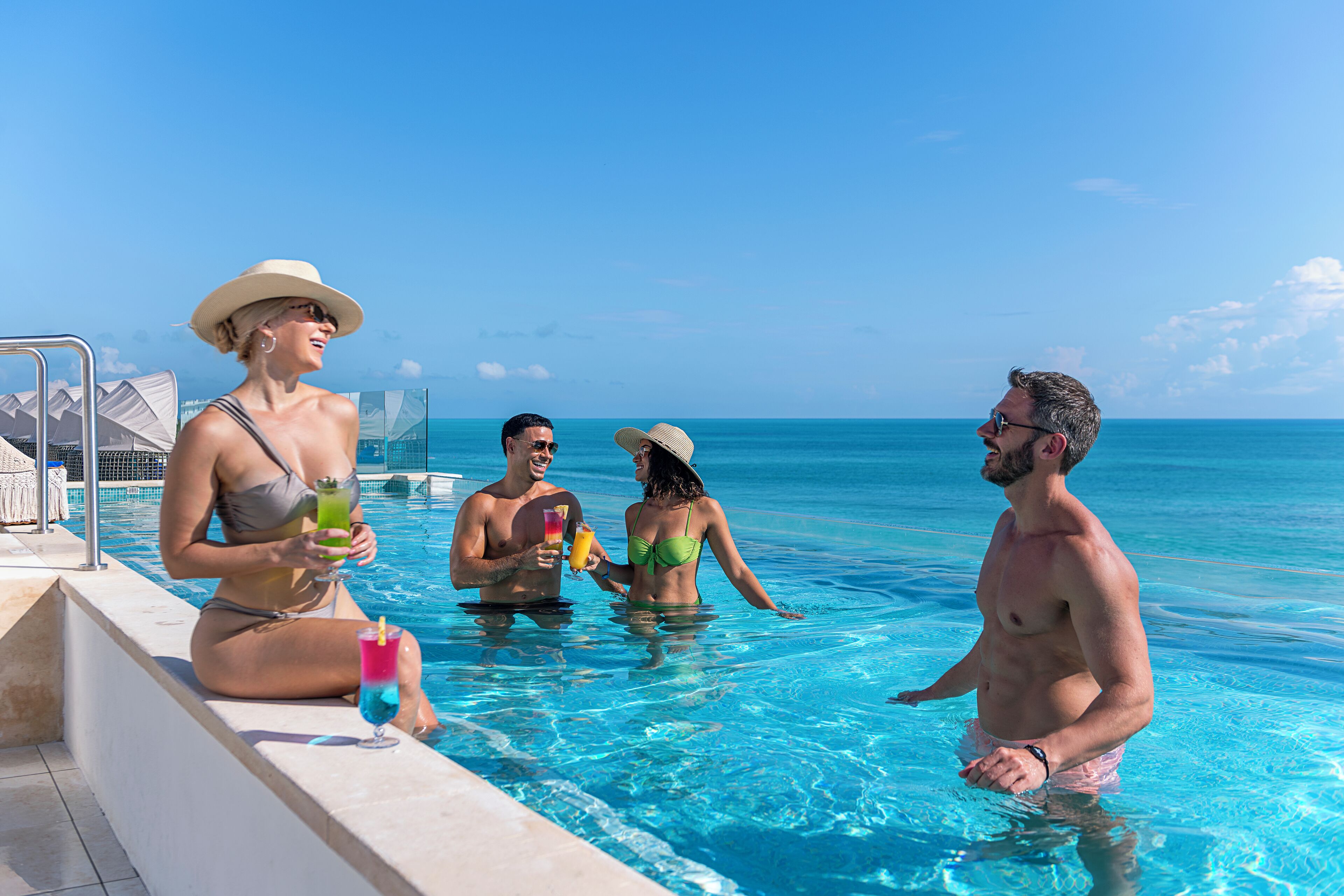 Escena junto a la piscina con agua azul cristalina y vista al océano.