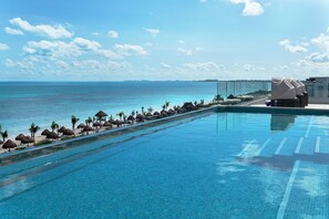 Une piscine avec vue sur l’océan, des palmiers et une plage.