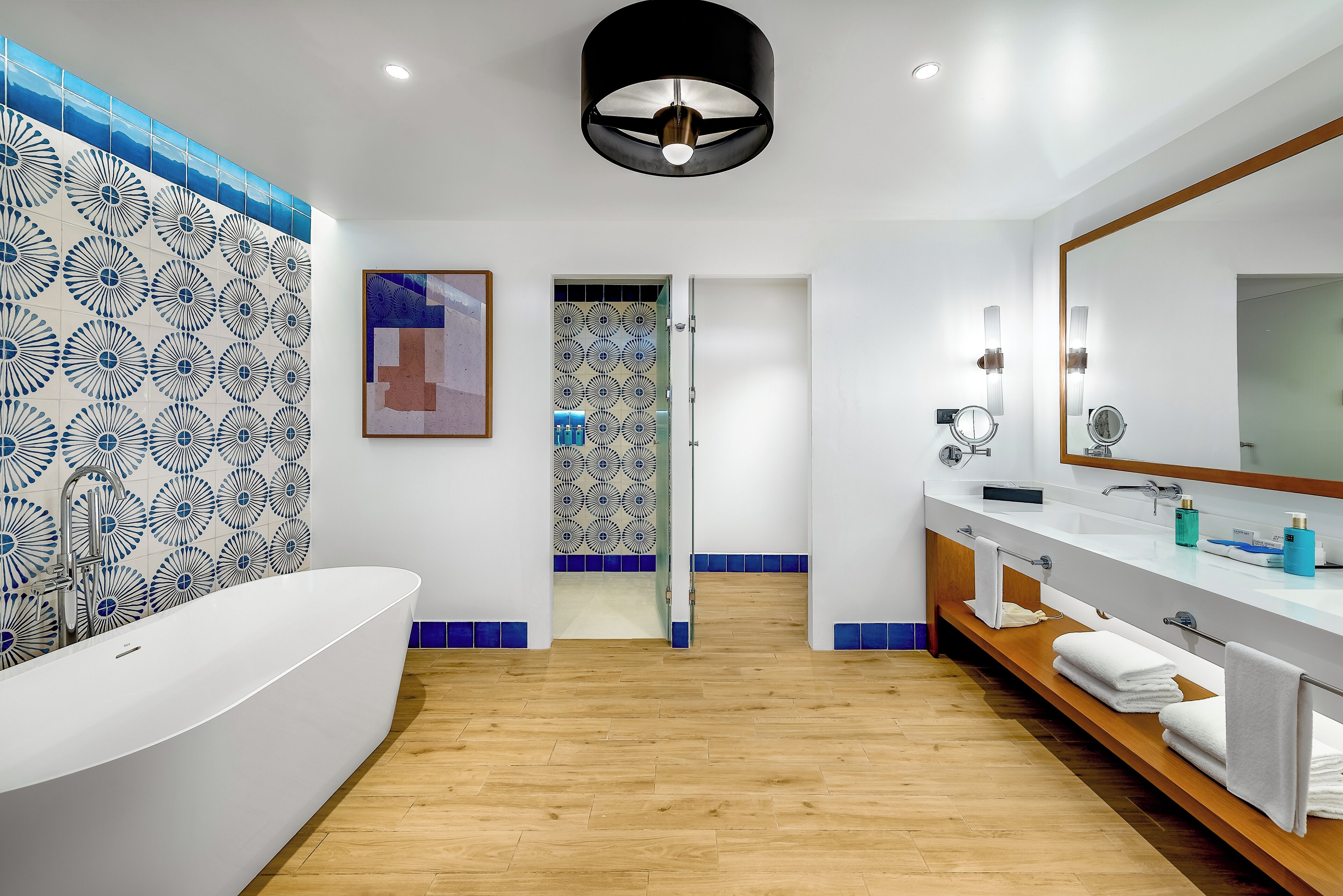 A modern bathroom with a freestanding bathtub, a large mirror, and a vanity with a sink and towel rack.