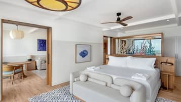 A modern hotel room with a large bed, a desk, and a dining area.