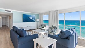 A modern living room with a large ocean view, a sofa set, a coffee table, and a painting on the wall. - 🌅 Gulf Front + Seasonal Comp Beach Setup | Shoreline 1081 - Stunning Views (Destin)