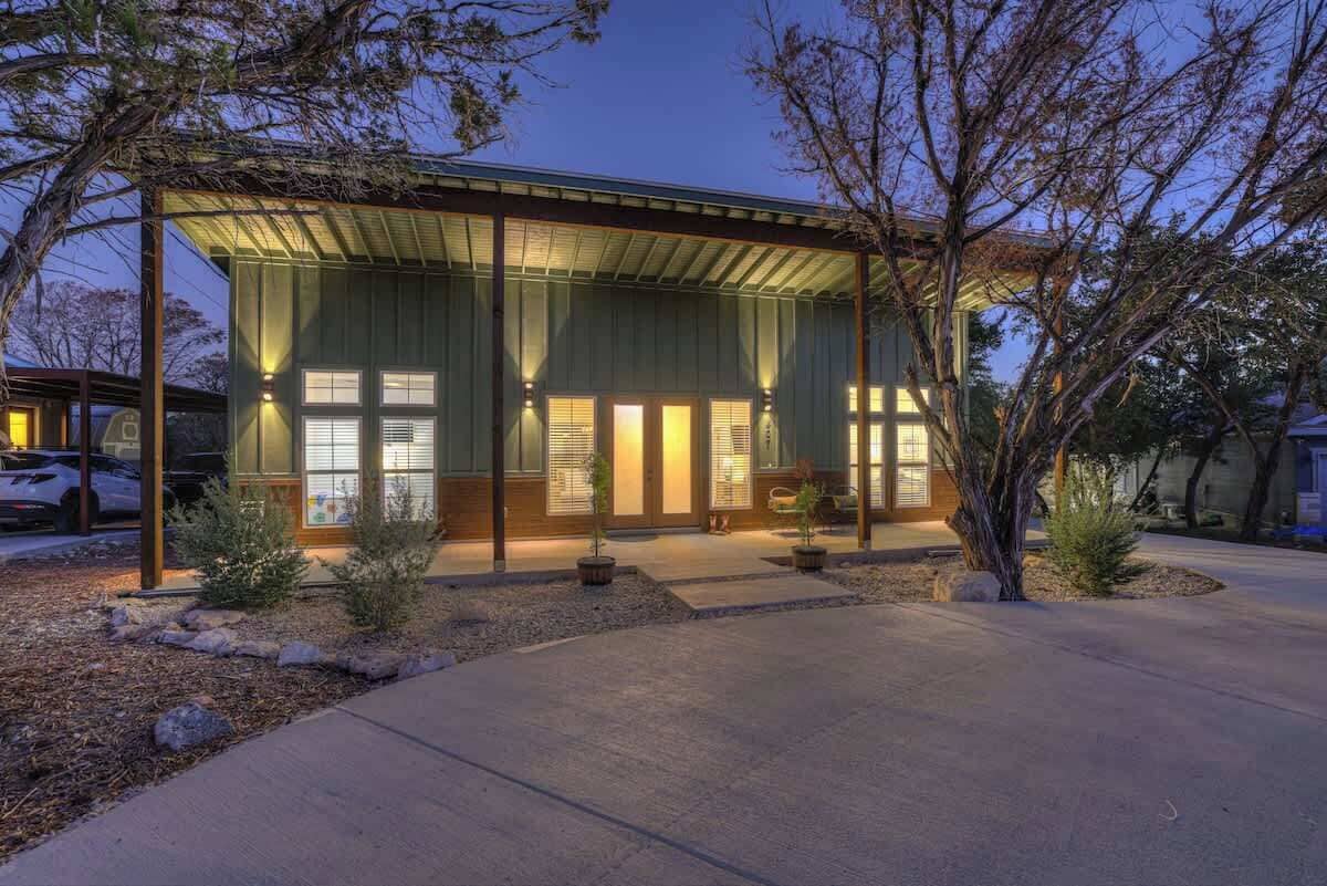 A modern house with a covered porch, large windows, and a well-maintained garden.