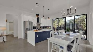 A modern kitchen with white cabinetry, a central island, and pendant lighting.